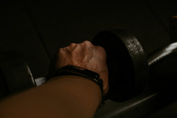 a person's hand holding a barbell in the dark