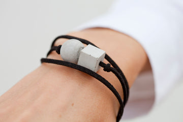 A person wearing a bracelet with two cubes on it