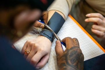 Someone is cutting a leather bracelet with scissors.