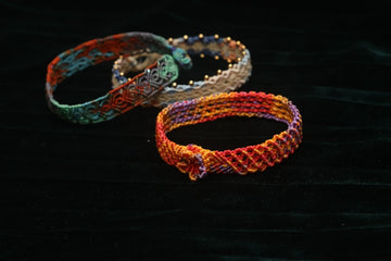 Three colorful woven bracelets on dark fabric