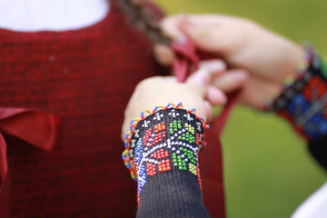 Hands braiding a young girl's hair with beaded bracelet